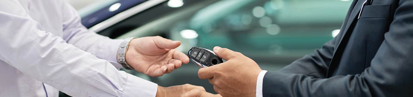 two people in a handshake exchanging keys to a new car